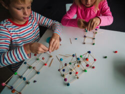 Due bambini stanno realizzando delle costruzioni con bastoncini e pezzi di plastilina