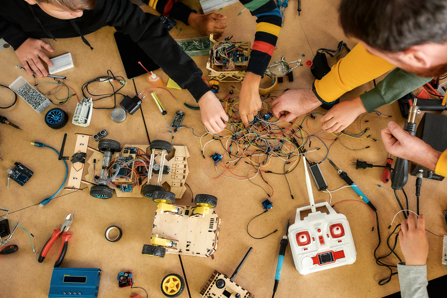 Immagine dall'alto di alcuni ragazzi intenti ad armeggiare con  dispositivi elettronici