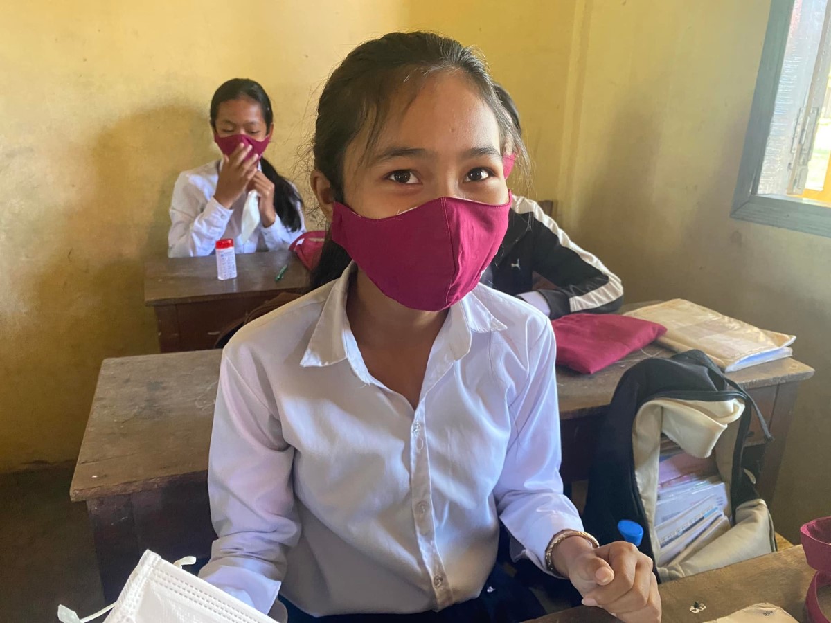 Una ragazza cambogiana indossa un mascherina seduta al suo banco