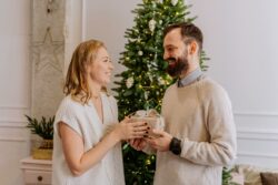 Due persone che si scambiano un regalo di Natale davanti all'albero in piedi